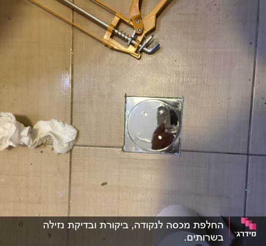 כלי עבודה צהוב ליד פתח ניקוז ברצפה